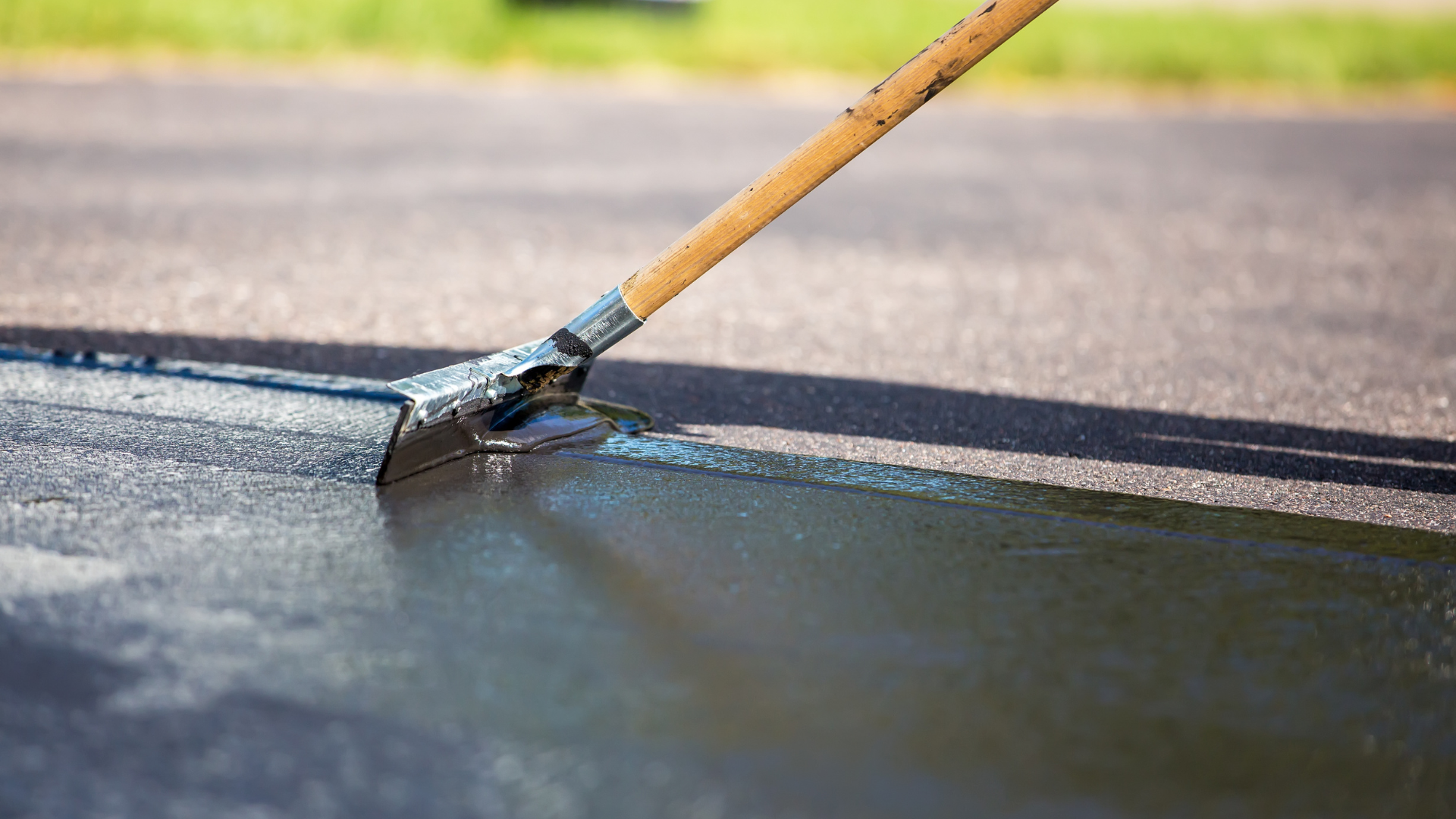 A newly spread gravel driveway leads toward a red house and a small yellow building in a residential neighborhood.