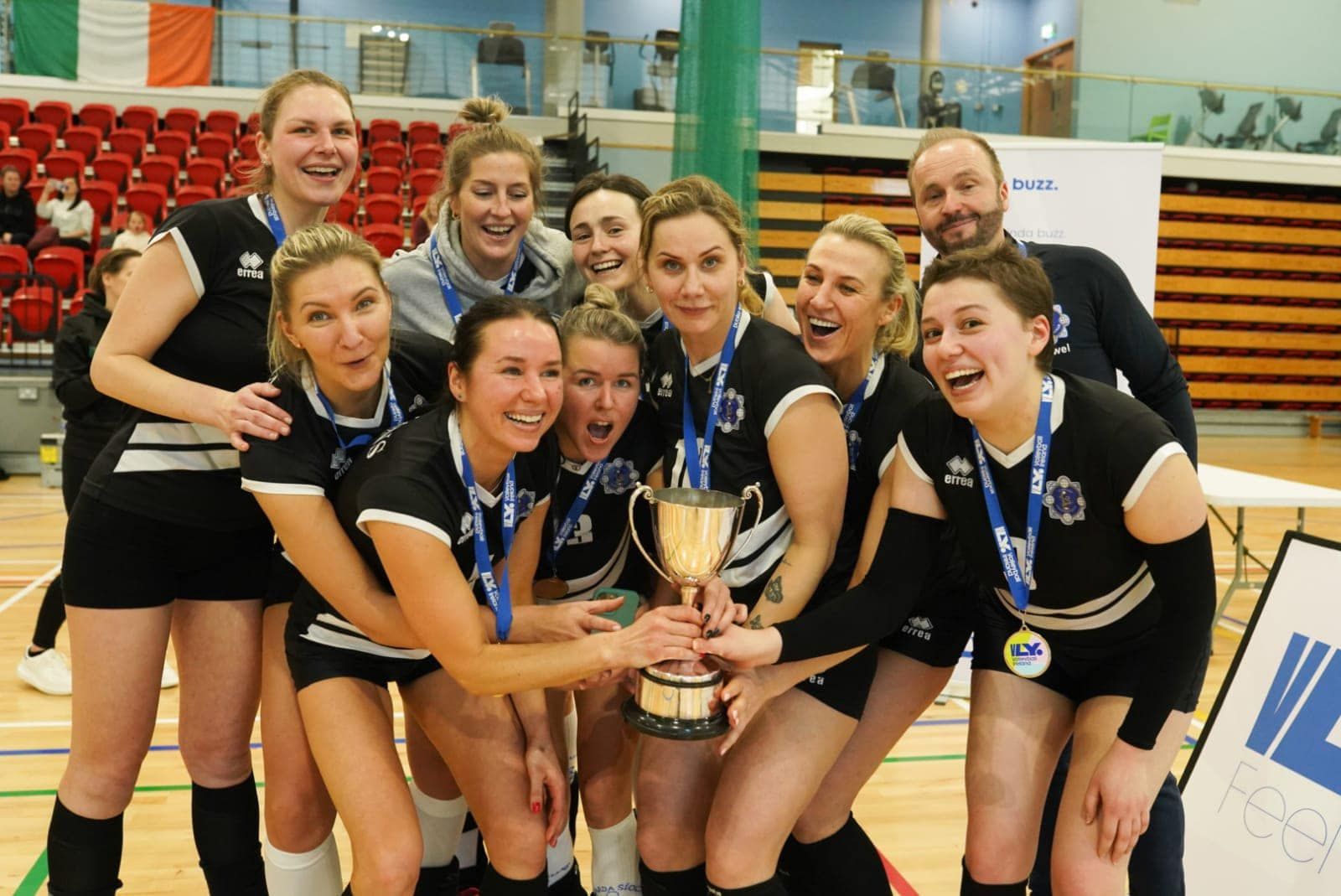 A group of female volleyball players holding a trophy