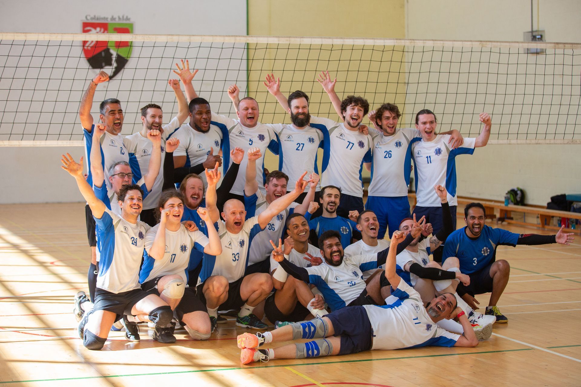A group of men are posing for a picture on a volleyball court.