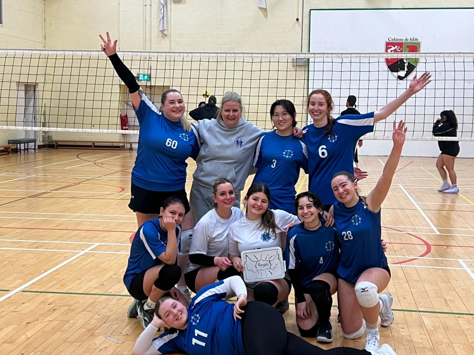 A group of young women are posing for a picture with a volleyball.