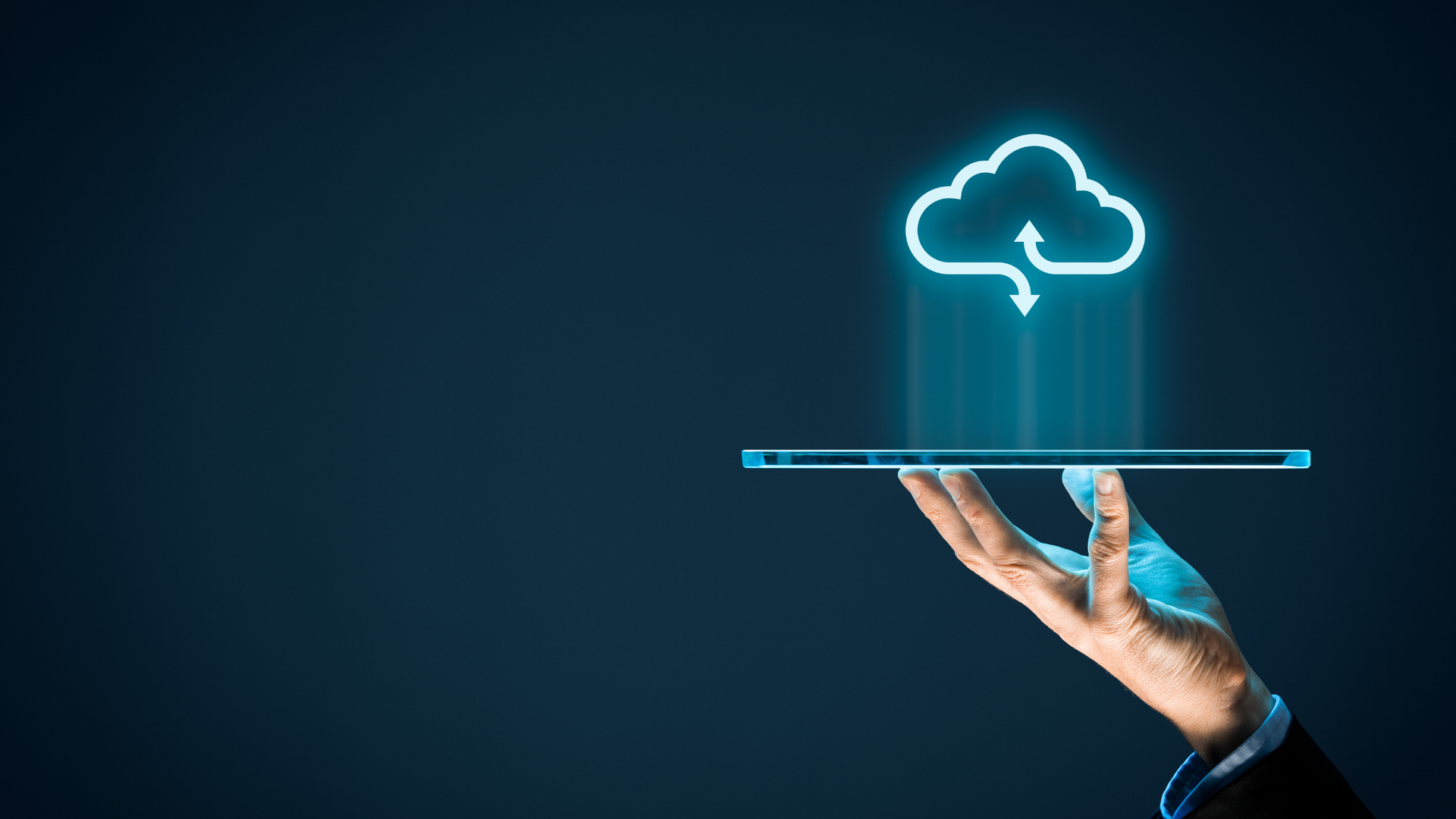 Hand holding a tablet with a glowing cloud icon above, against a dark blue background.