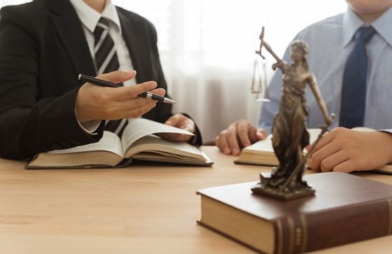Two lawyers are sitting at a table with a statue of justice. Two lawyers are sitting at a table with a statue of justice.