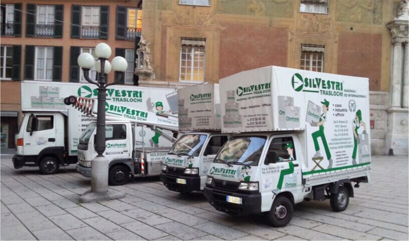 Una fila di camion in movimento è parcheggiata davanti a un edificio