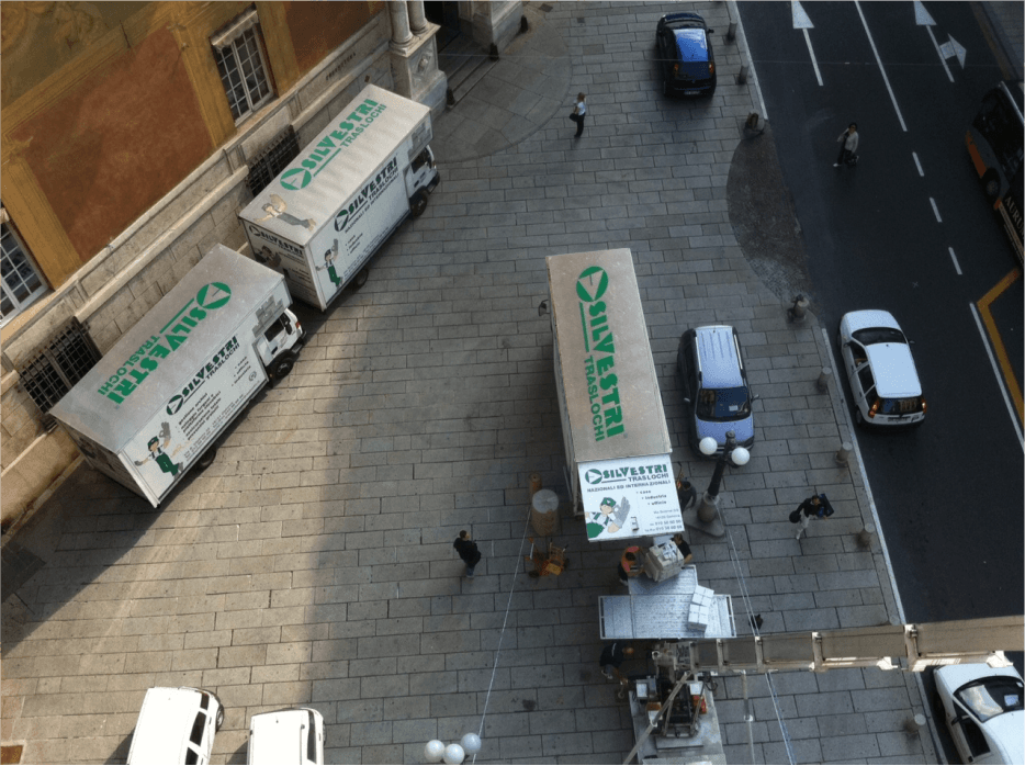 Una vista aerea di una strada cittadina con camion in movimento parcheggiati sul marciapiede
