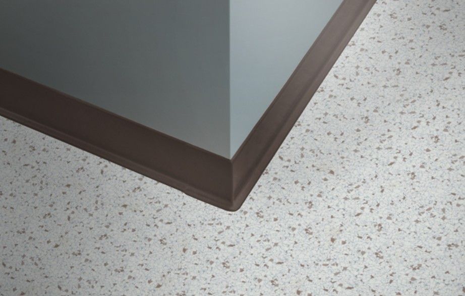 Beige-toned wall with light shining across a wooden floor and baseboard.