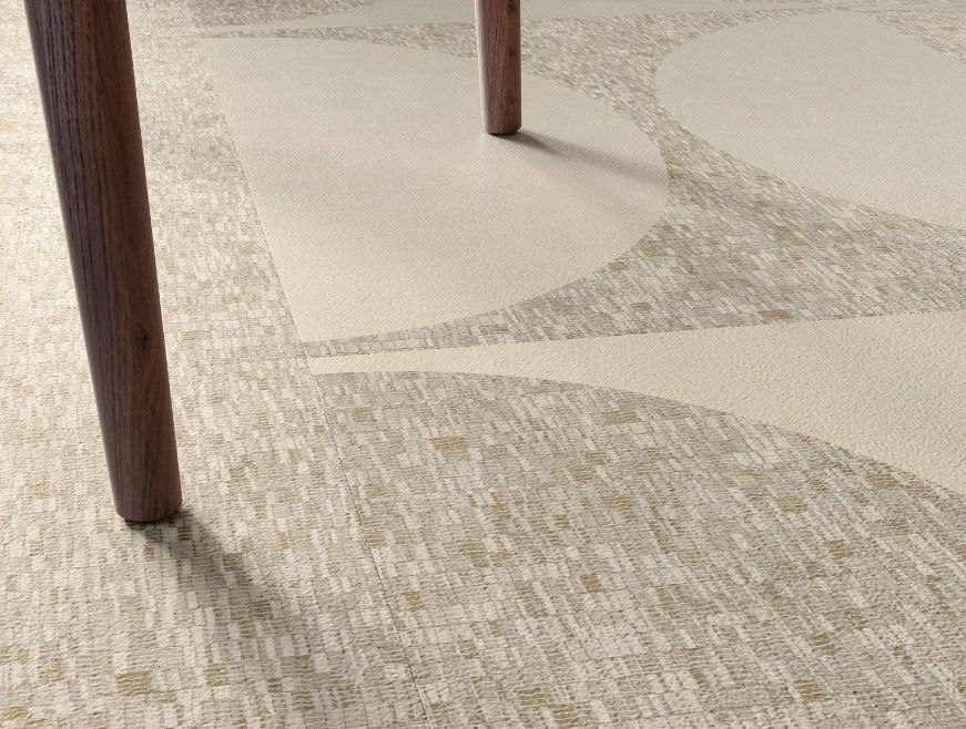 Wooden table legs on a mosaic-patterned floor with beige geometric shapes.
