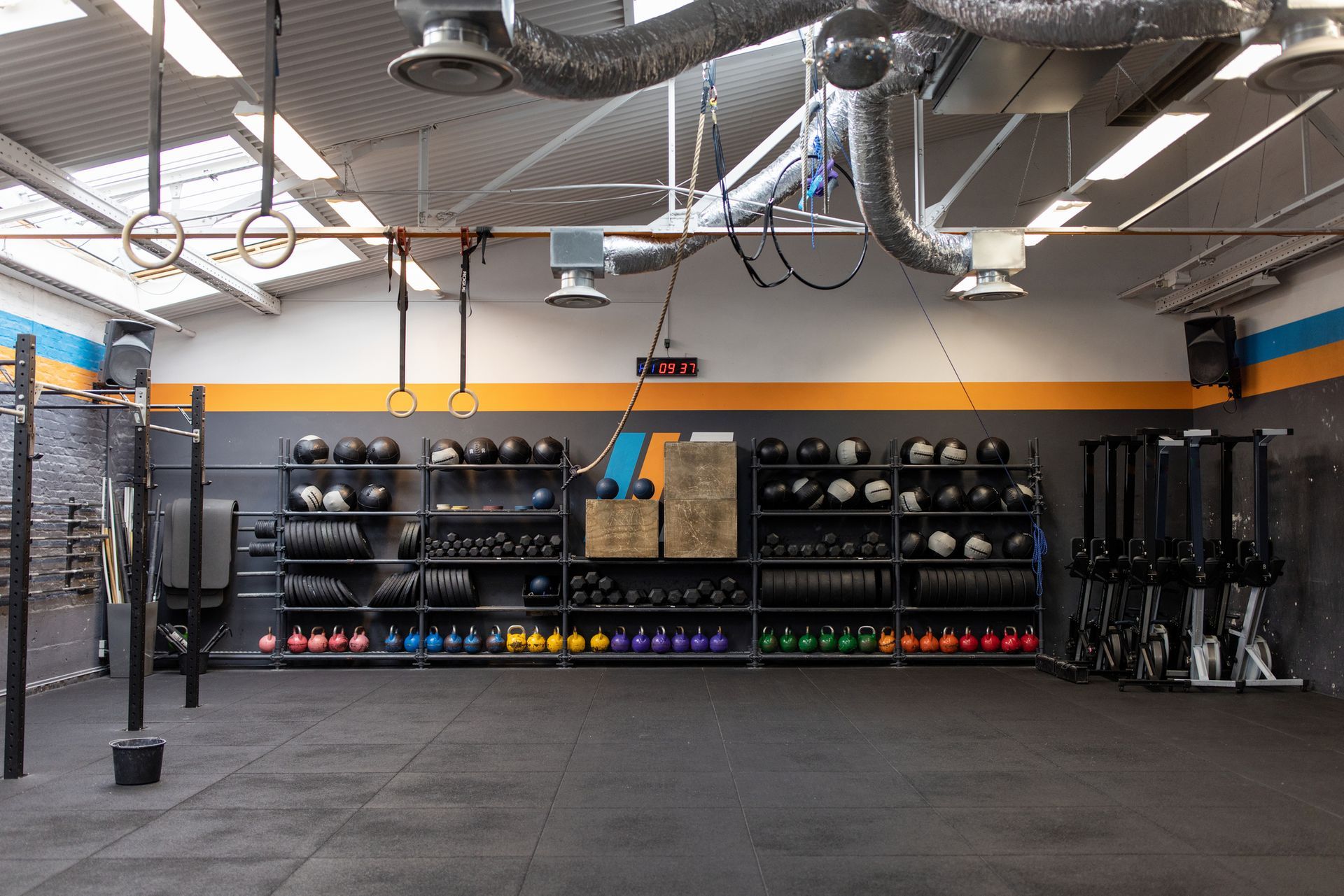 Gym interior with treadmills near windows, exercise machines, and black ceiling.