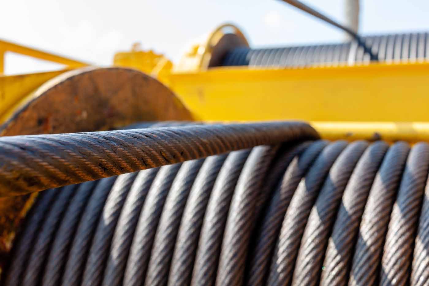 A close up of a spool of wire on a yellow crane.