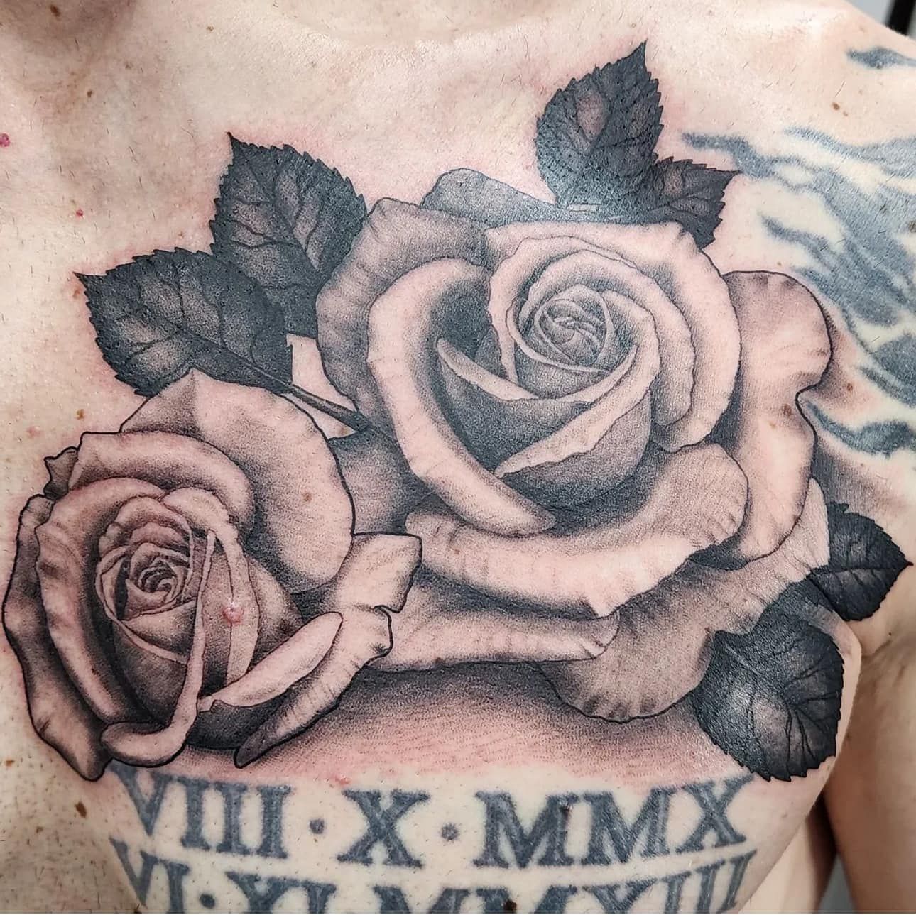 Black and gray rose tattoo with Roman numerals on skin