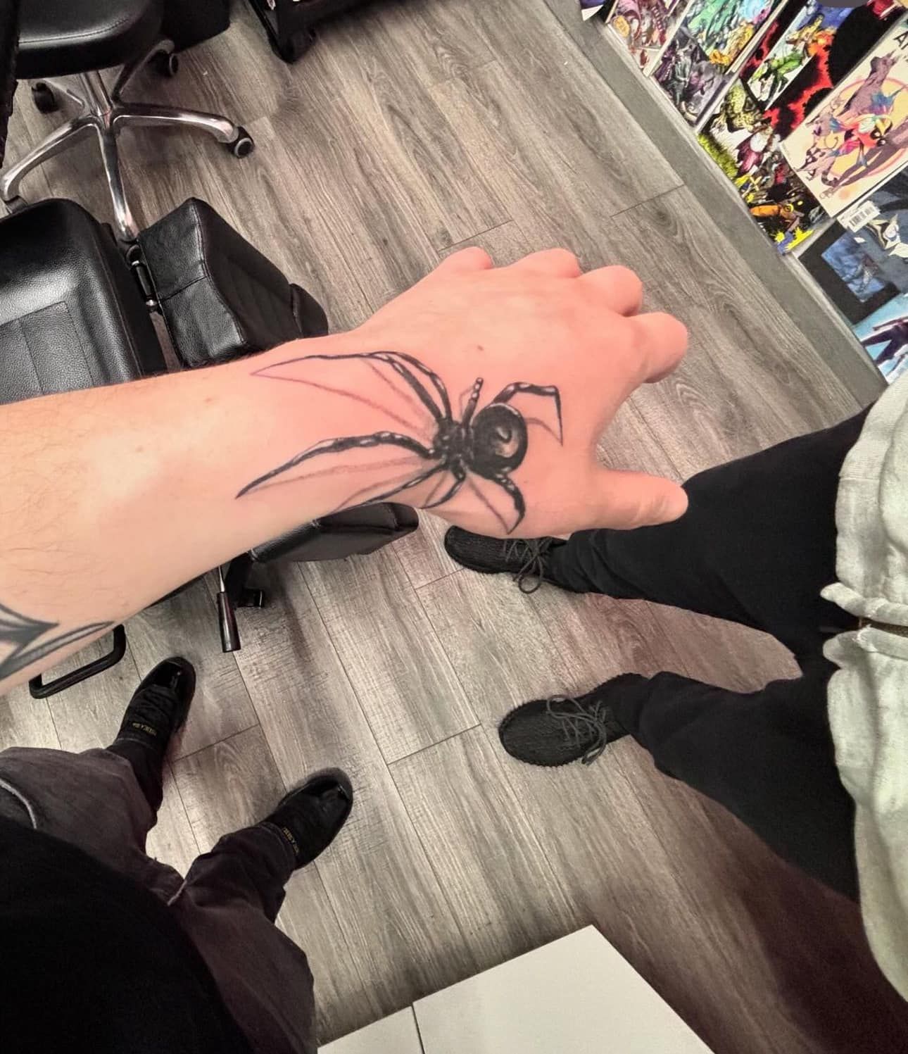 Hand with a large black spider tattoo at a comic shop, viewed from above.