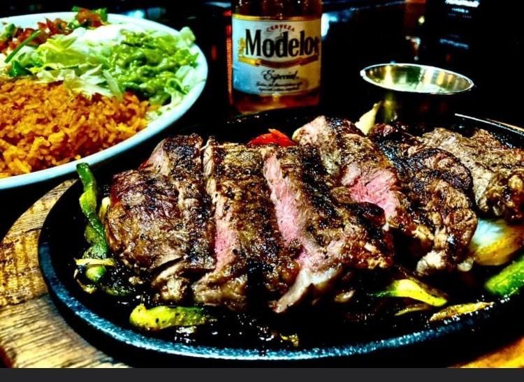 A plate of food with a bottle of modelor beer in the background