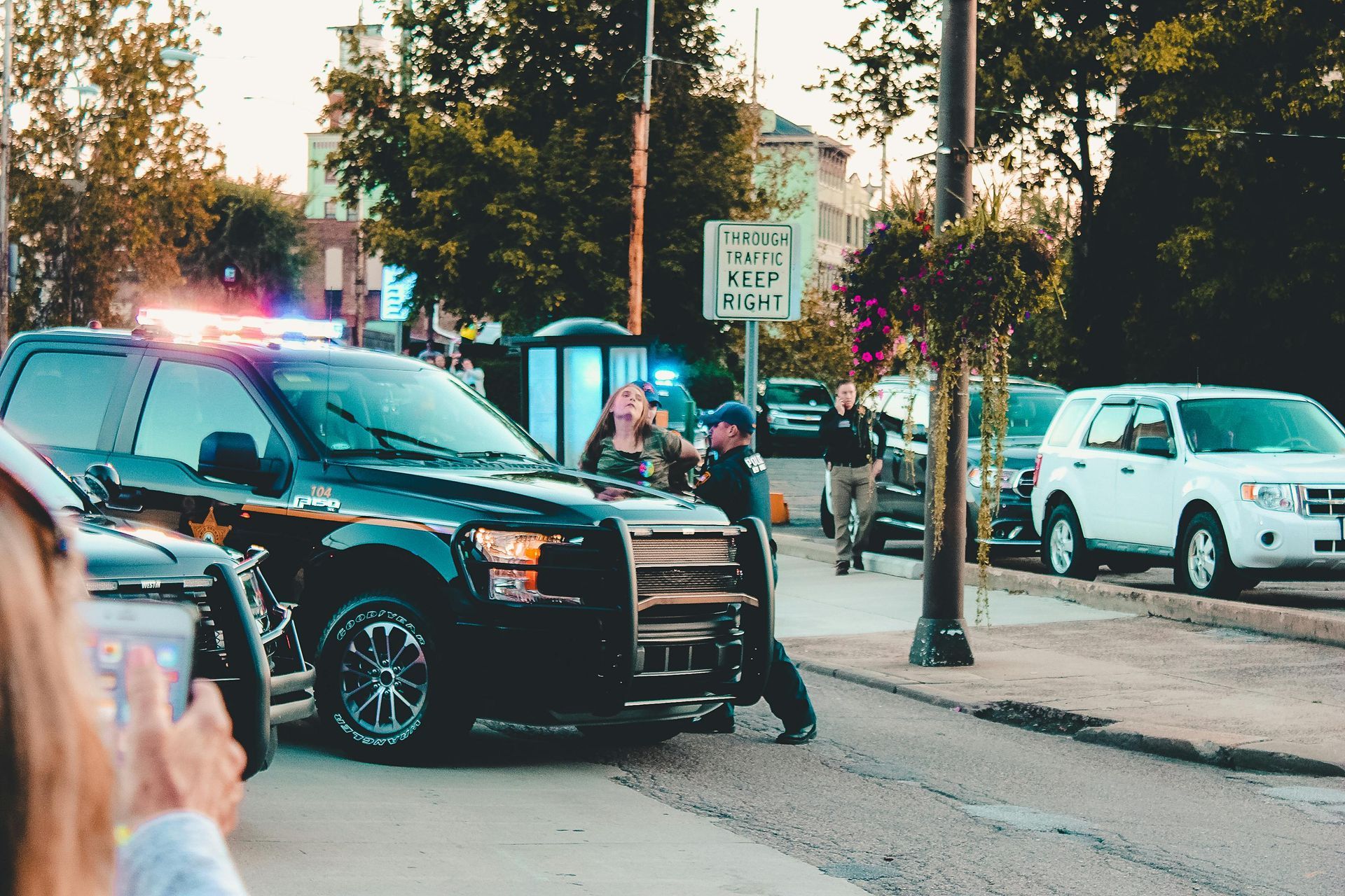 A woman is taking a picture of a police car on the street.
