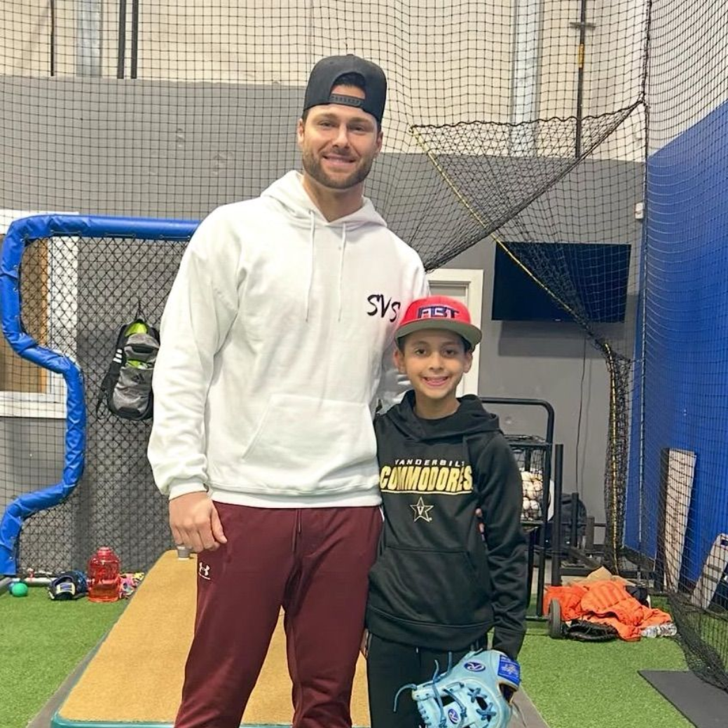 Tally Baseball coach with young player smiling inside training facility