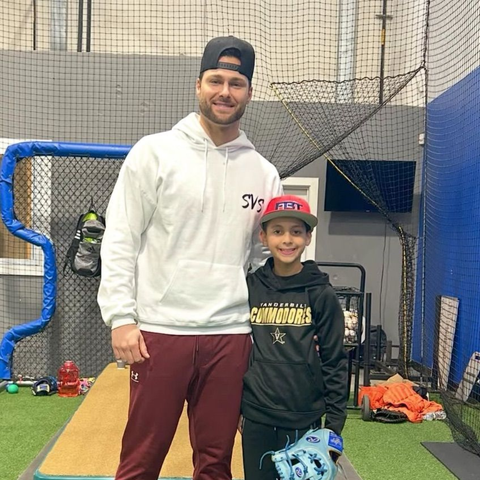 Baseball coach with youth player inside Tally Baseball indoor training cage