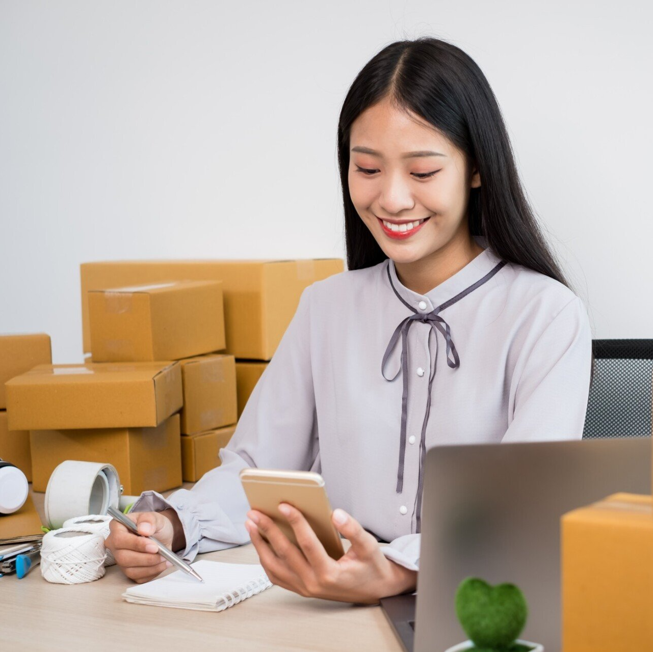 young  happy asian business woman with many orders boxed and ready to go