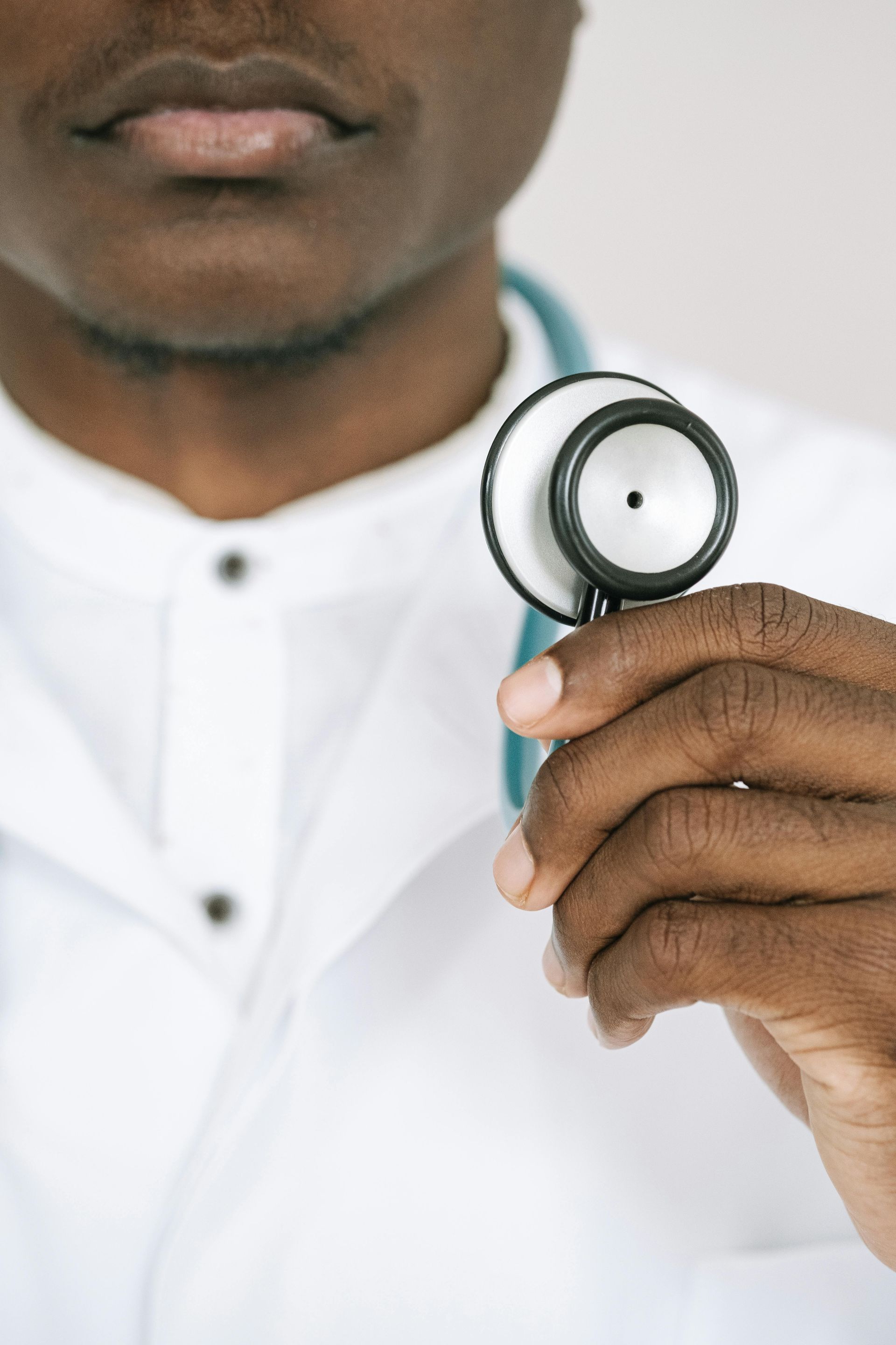 Doctor holding a stethoscope in front of a white coat.
