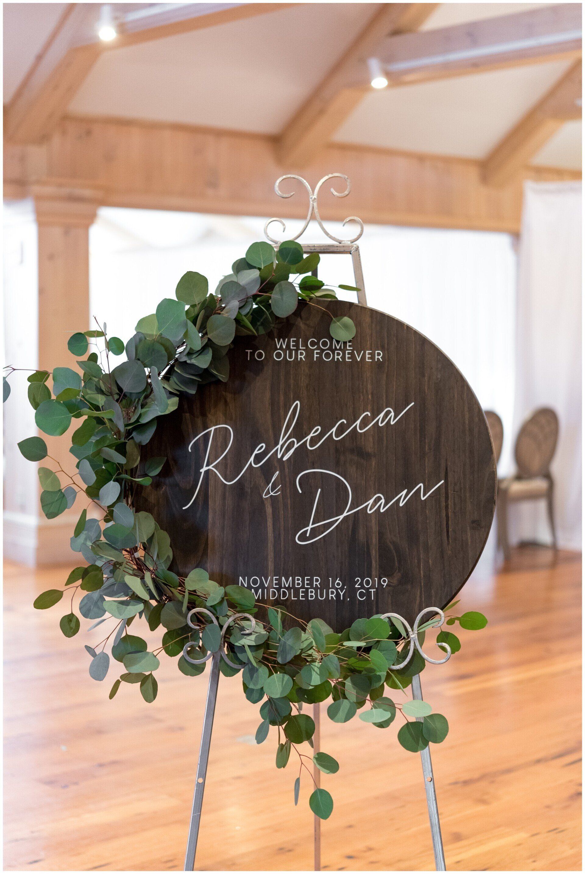 Wood circle wedding welcome sign with eucalyptus leaves along the edge