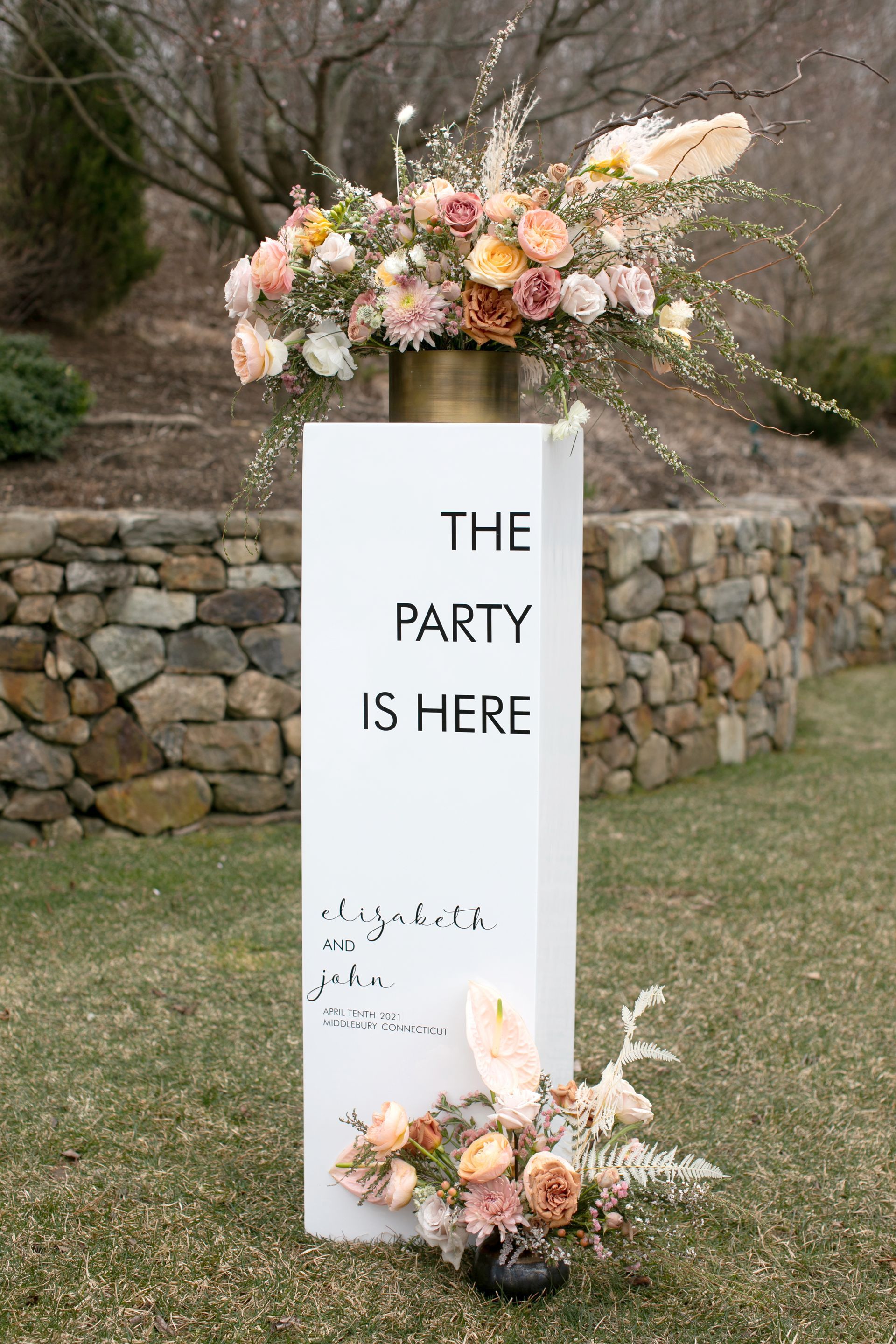 Tall white welcome wedding sign with boho flower arrangement on top