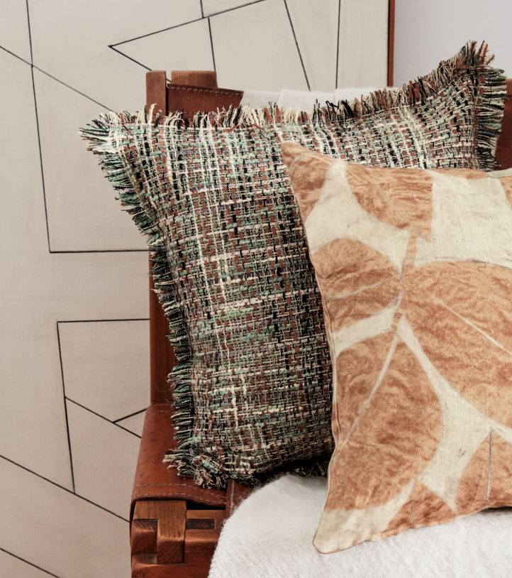 Ein braunes und weißes Kissen liegt auf einem Bett