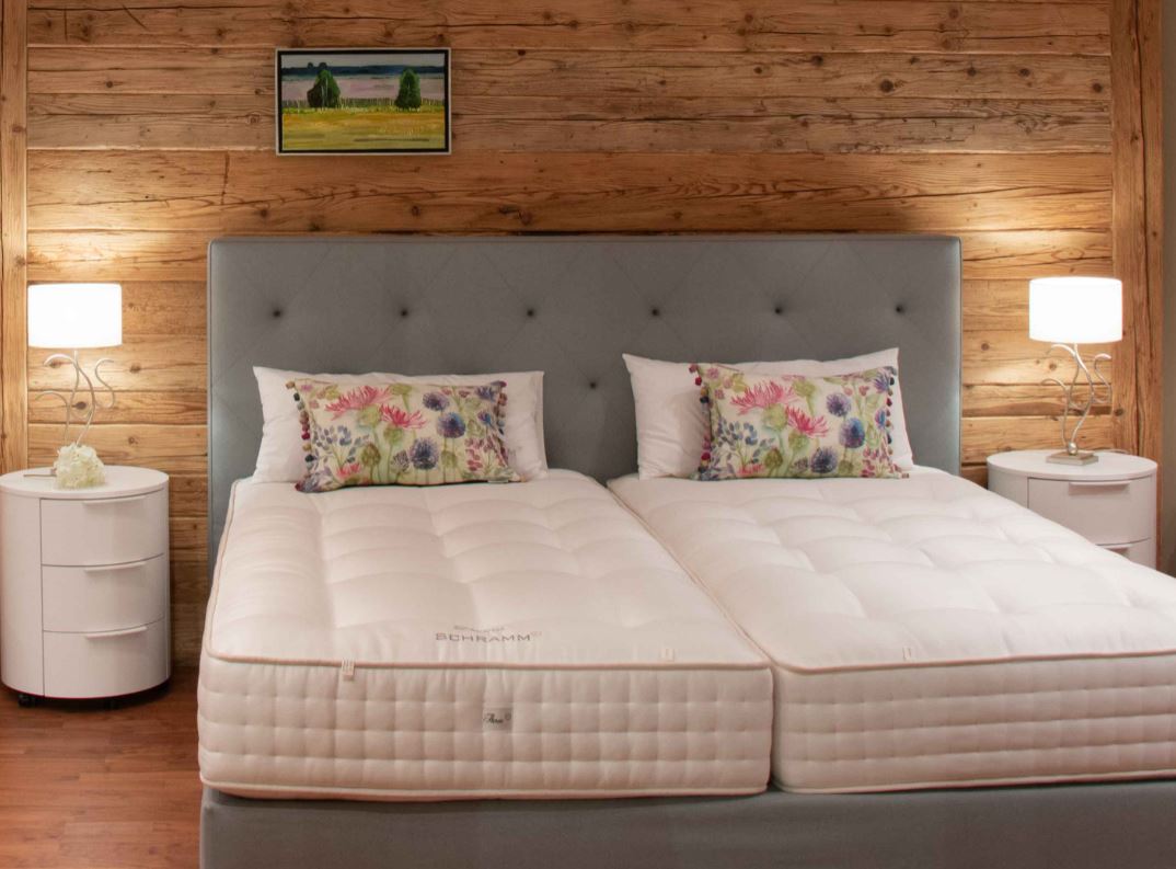 Ein Schlafzimmer mit zwei Betten, zwei Nachttischen und einer Holzwand.