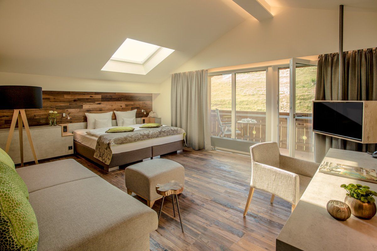 Ein Hotelzimmer mit Bett, Couch, Schreibtisch, Stuhl und Fernseher.