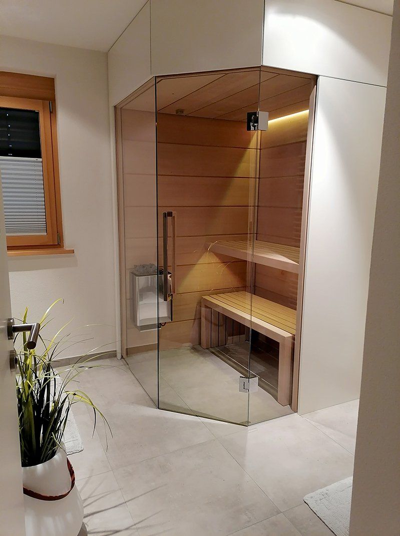 Ein Badezimmer mit Glastür und eine Holzsauna.