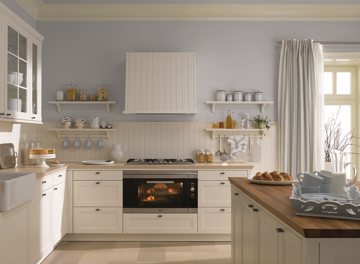 Eine Küche mit weißen Schränken und einer Holzarbeitsplatte