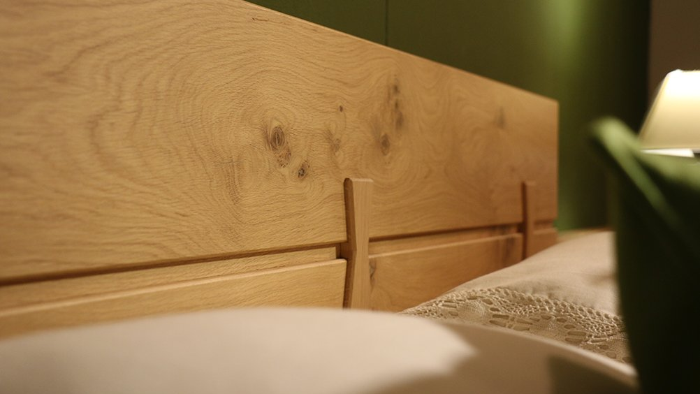 Eine Nahaufnahme eines hölzernen Kopfteils eines Bettes.