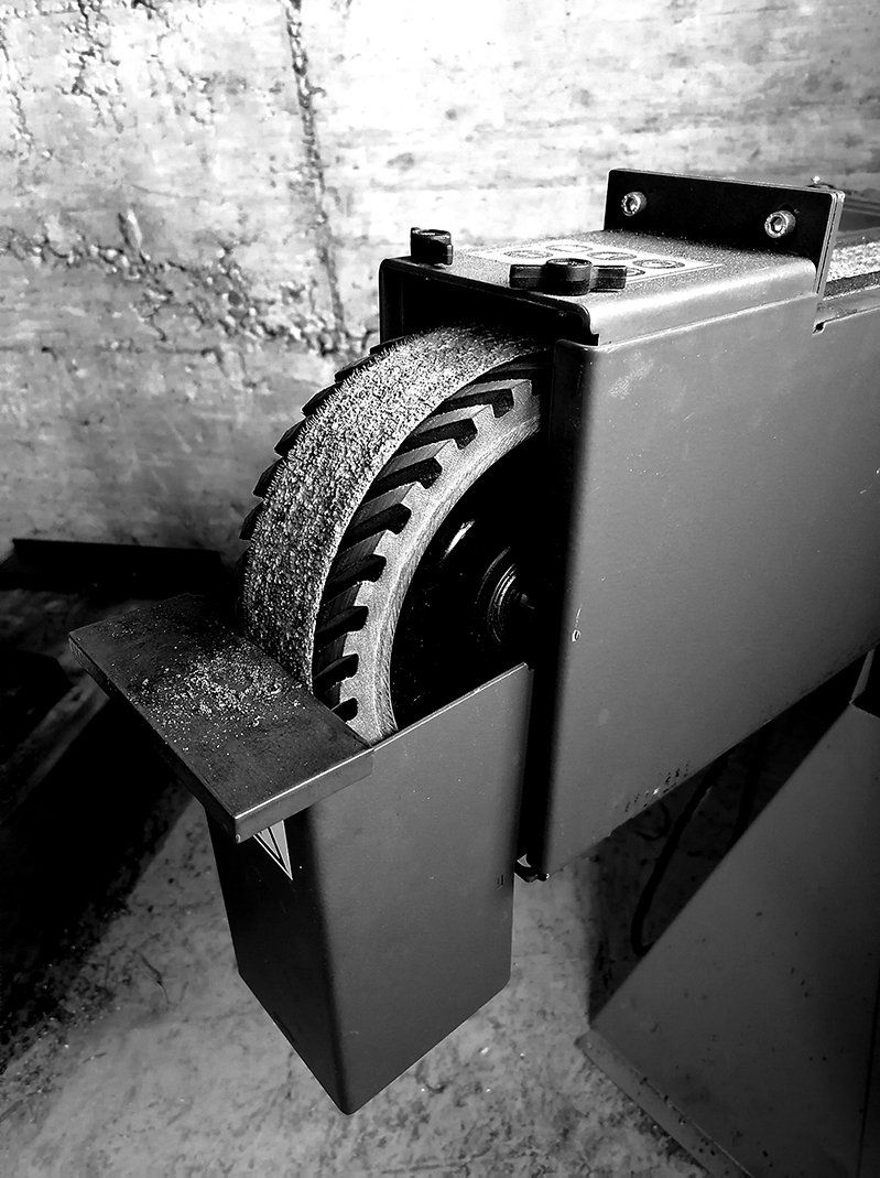 Ein Schwarzweißfoto einer Maschine mit einer Backsteinmauer im Hintergrund.