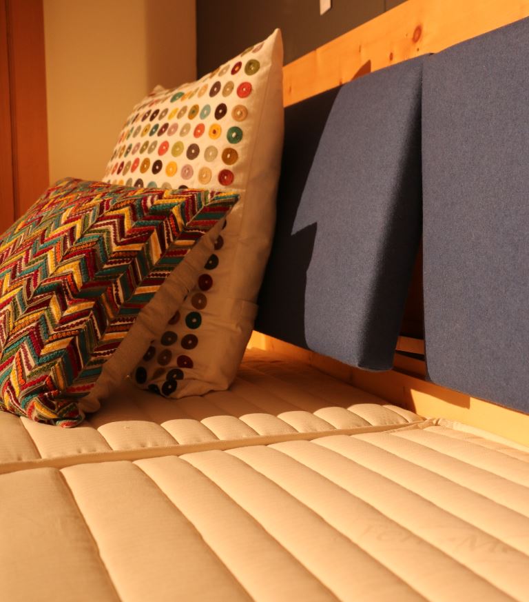 Ein Bett mit zwei bunten Kissen darauf