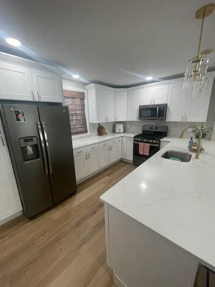 Bright white kitchen with white cabinets, light countertops, and dark stainless steel appliances.