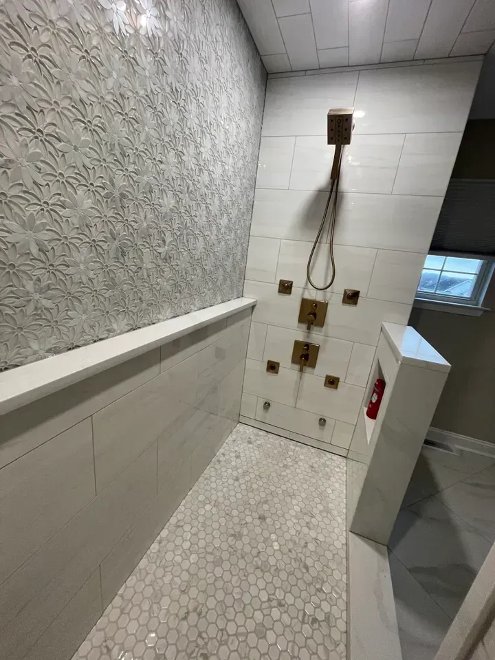 White-tiled shower with patterned accent wall and hexagon tile floor.
