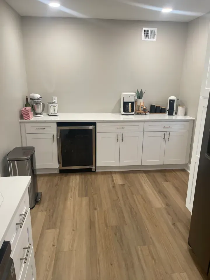 White cabinets with appliances, countertop, and a mini-fridge in a kitchen space.