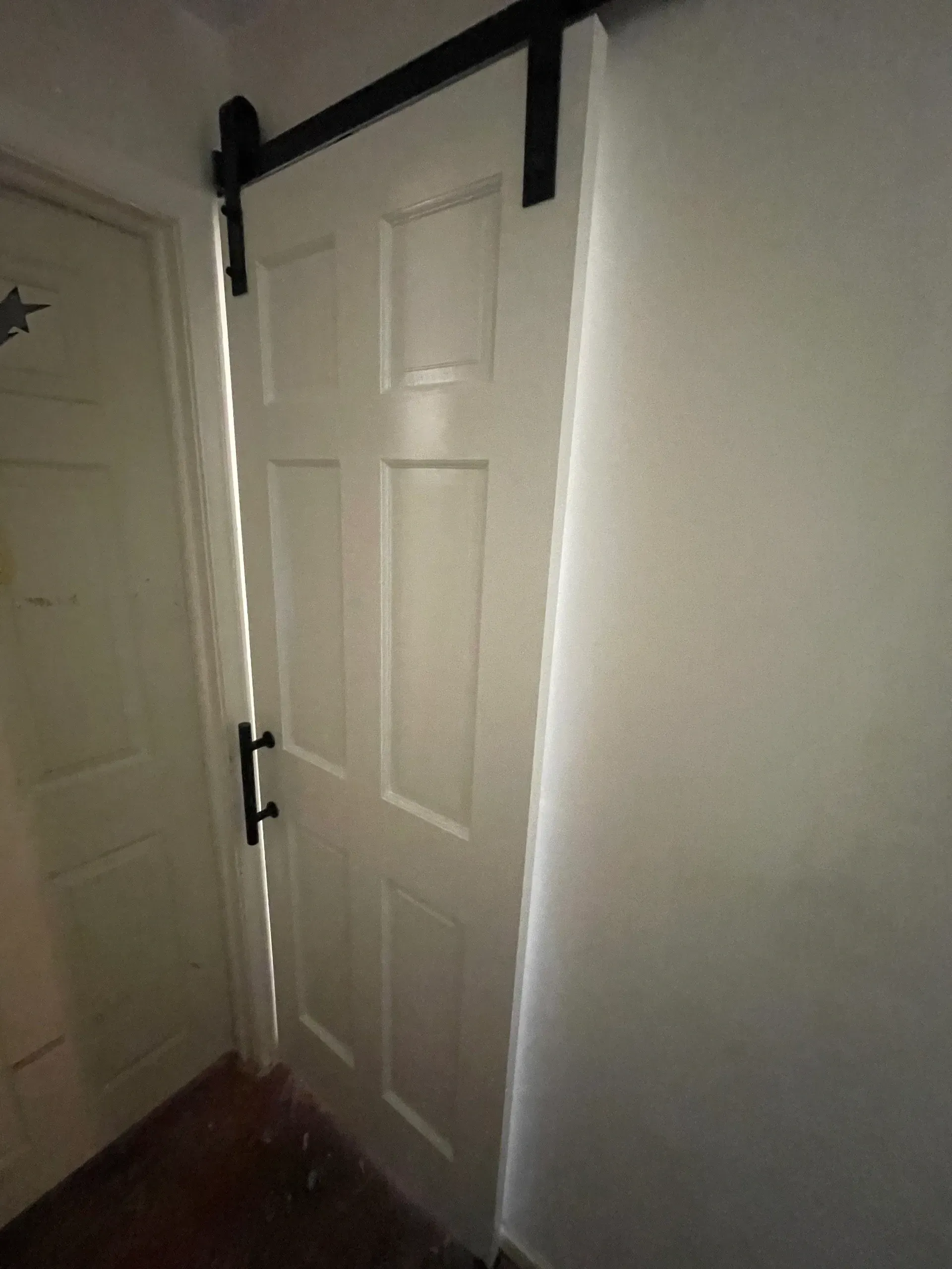 White sliding door with black hardware on a white wall.