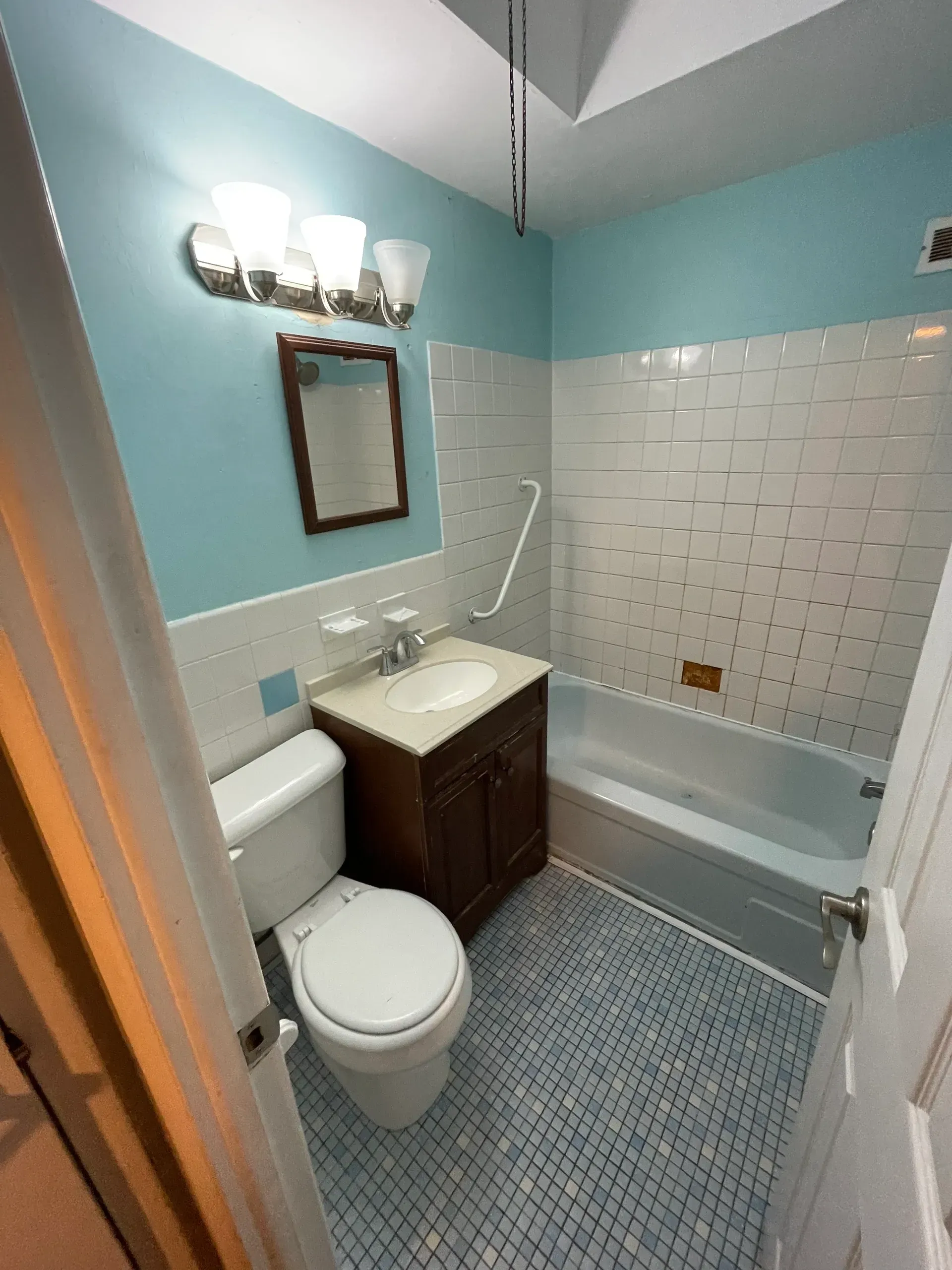 Bathroom with blue walls and tile, white fixtures, and a dark wood vanity.