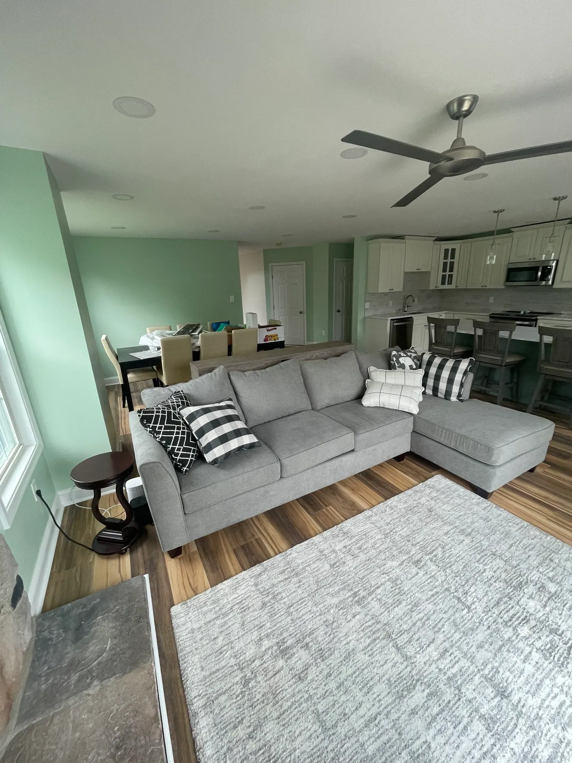 Living room with gray sectional sofa, rug, and kitchen in the background. 