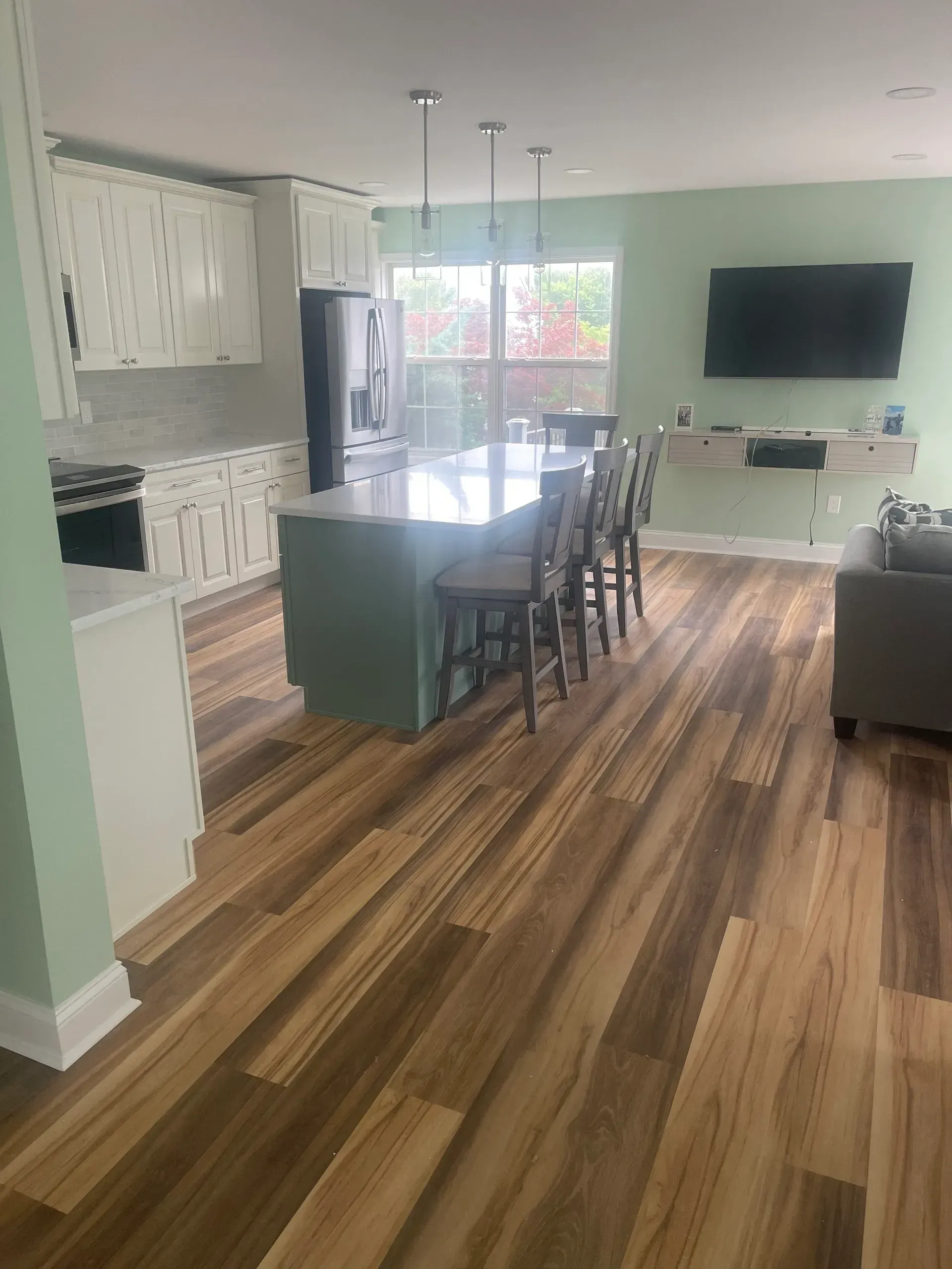 Spacious kitchen with a large island, bar stools, and hardwood floors.