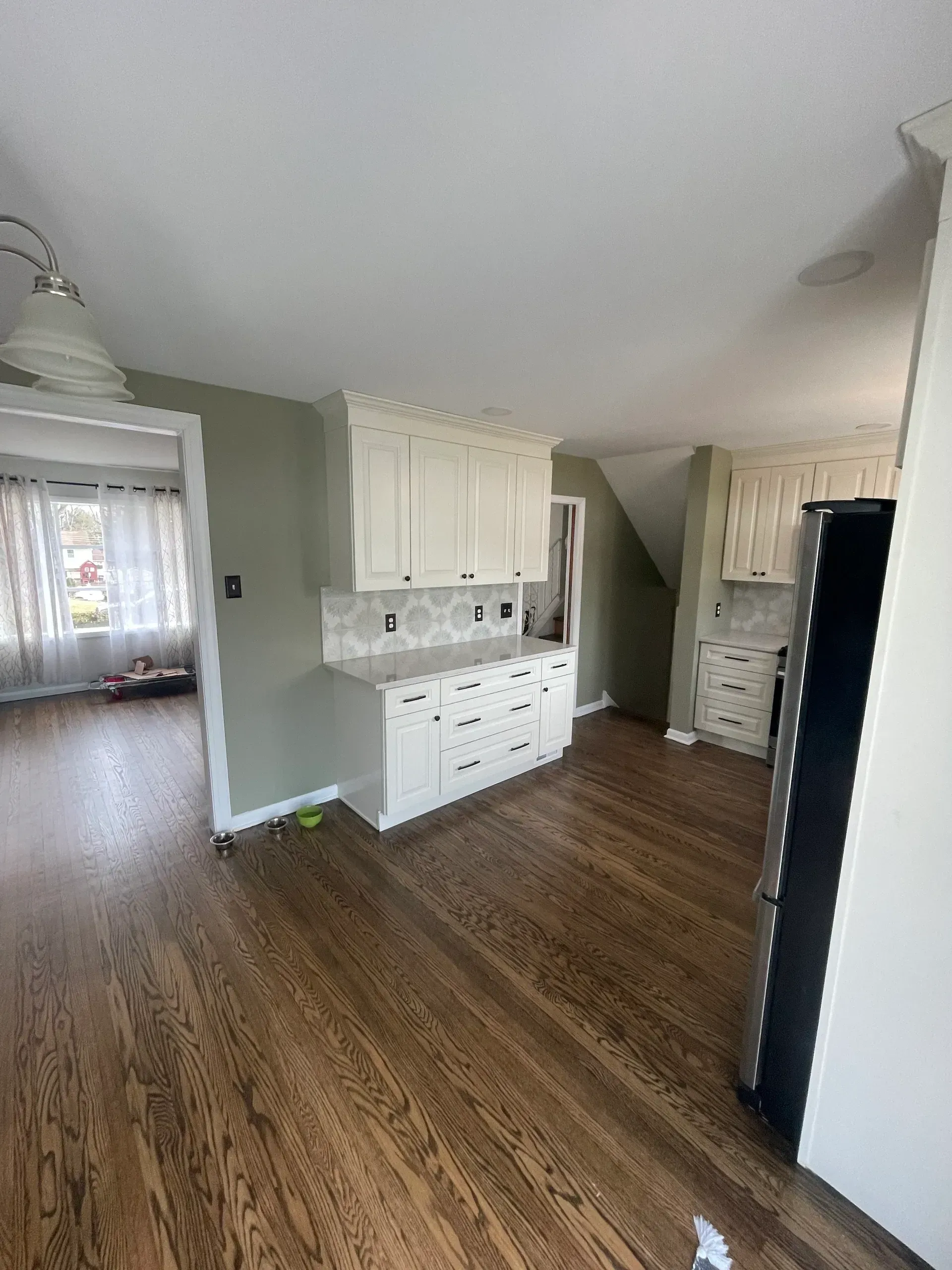 Kitchen with white cabinets, light-colored countertops, hardwood floors, and sage green walls.