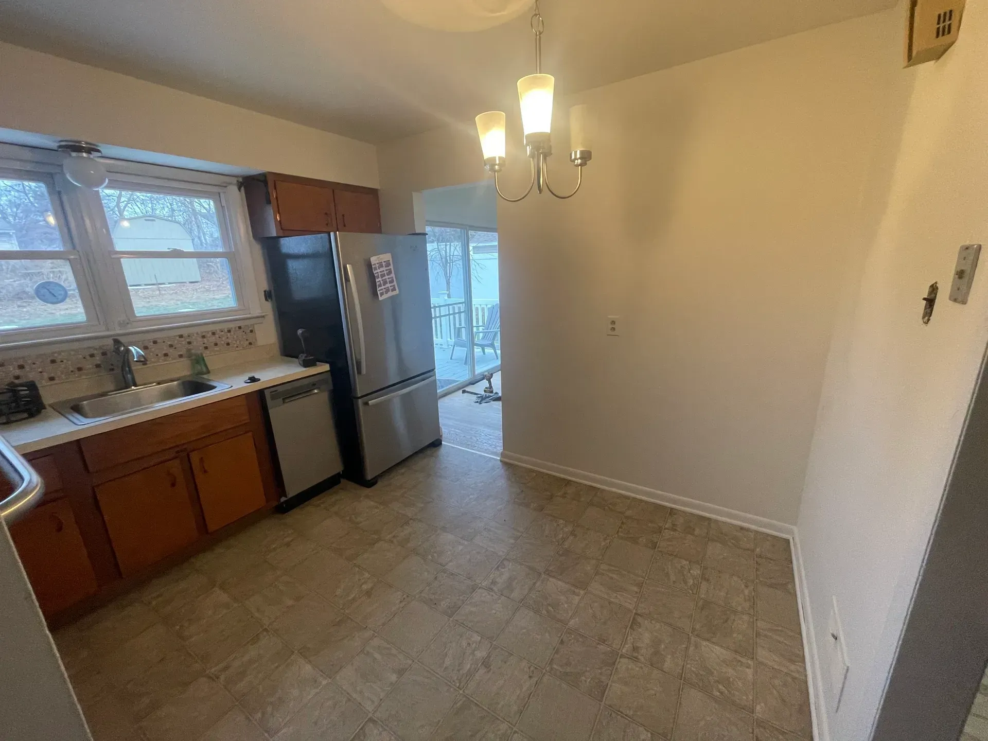 Kitchen with brown cabinets, stainless steel appliances, and a hanging light fixture.