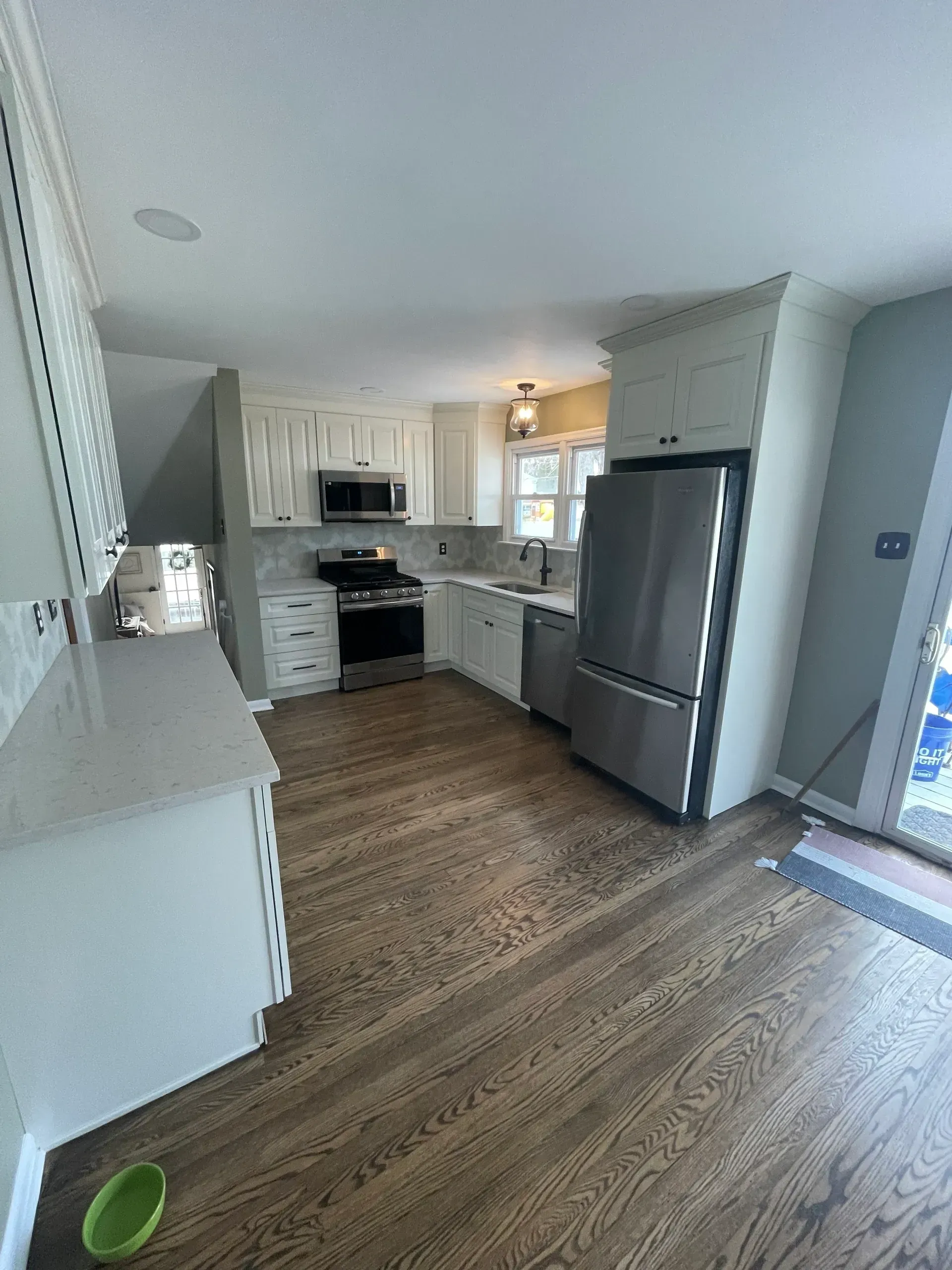 Bright, modern kitchen with white cabinets, stainless steel appliances, and wood flooring.
