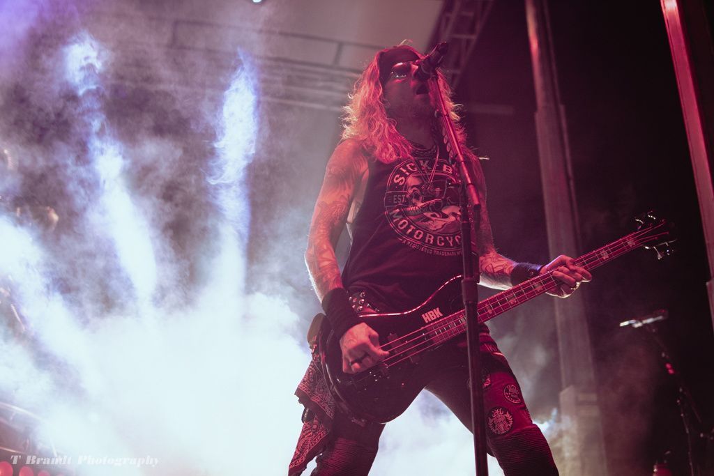 A man is playing a guitar and singing into a microphone on a stage.