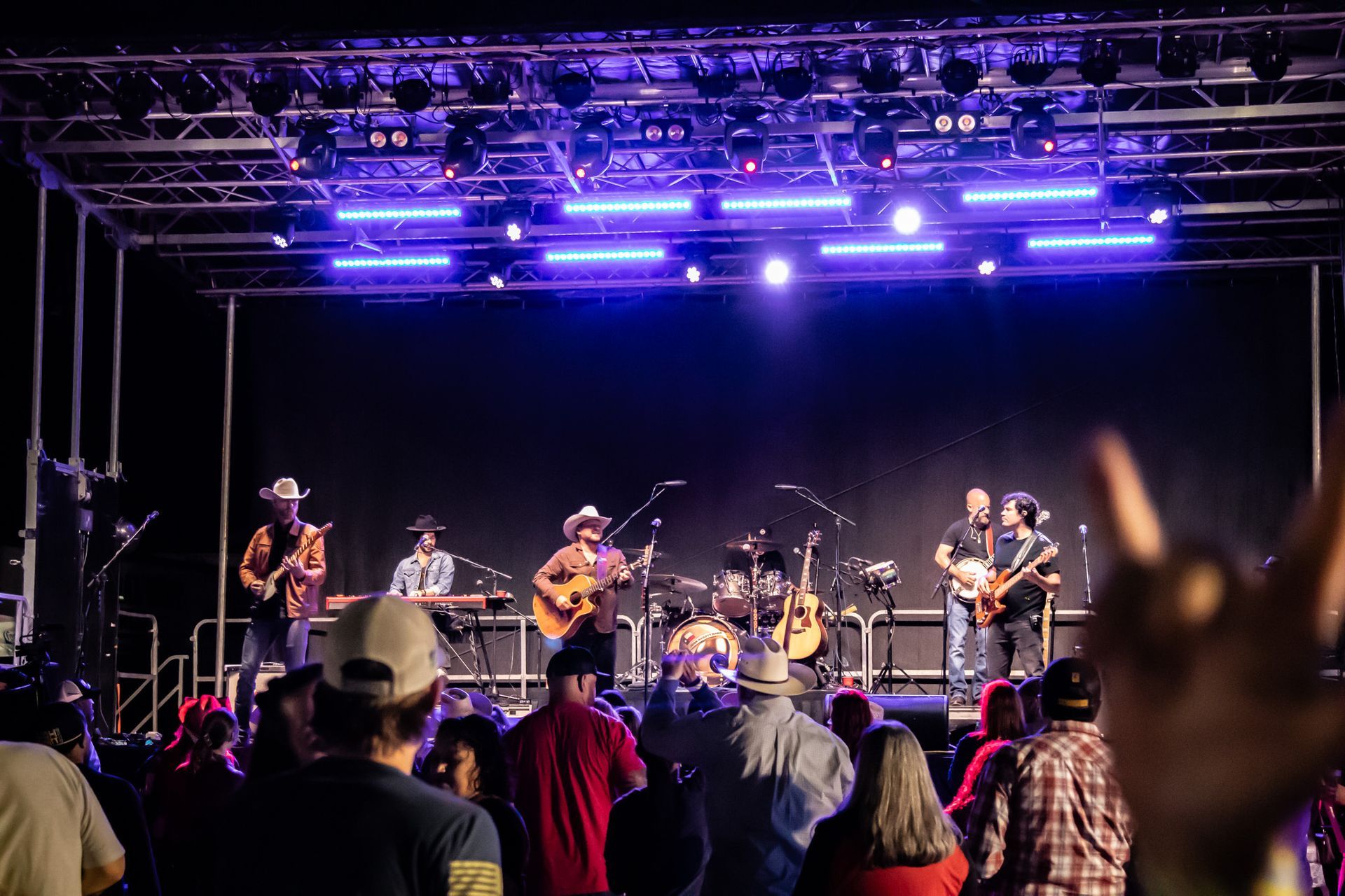 A group of people are standing in front of a stage at a concert.