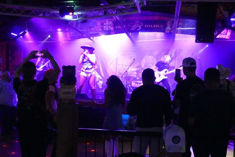 A man is playing an electric guitar in front of a drum set.