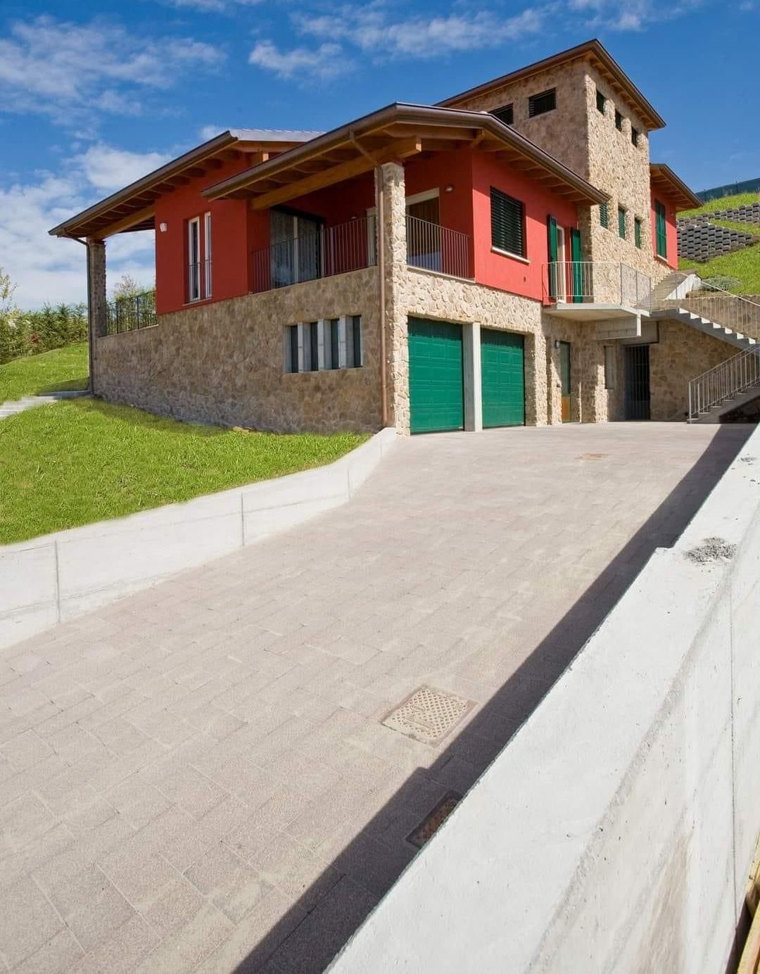 una grande casa rossa e marrone con due garage verdi