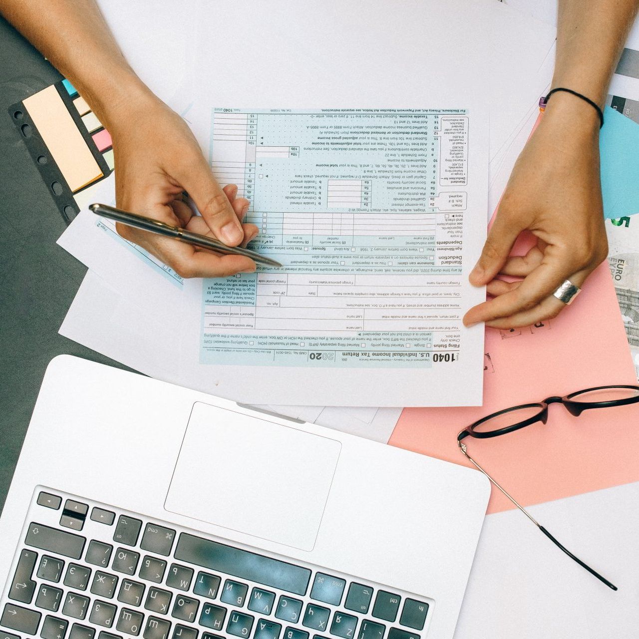 A person is filling out a tax form with a pen