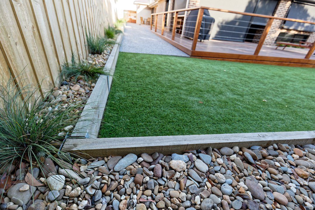 A lawn with rocks and a fence in the background.