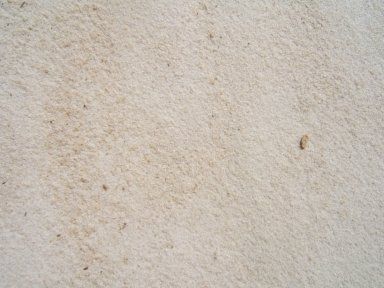 A close up of a white carpet with a stain on it.