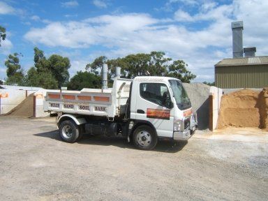 A white dump truck is parked in front of a pile of dirt