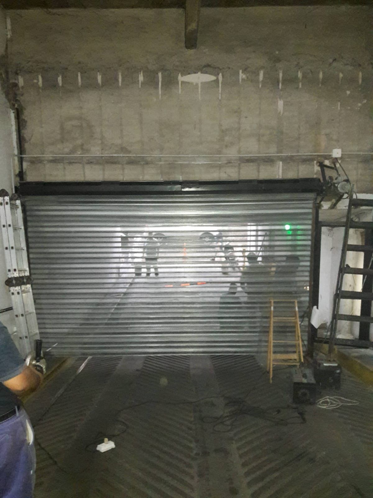 Un hombre está parado frente a una puerta de garaje con una escalera.