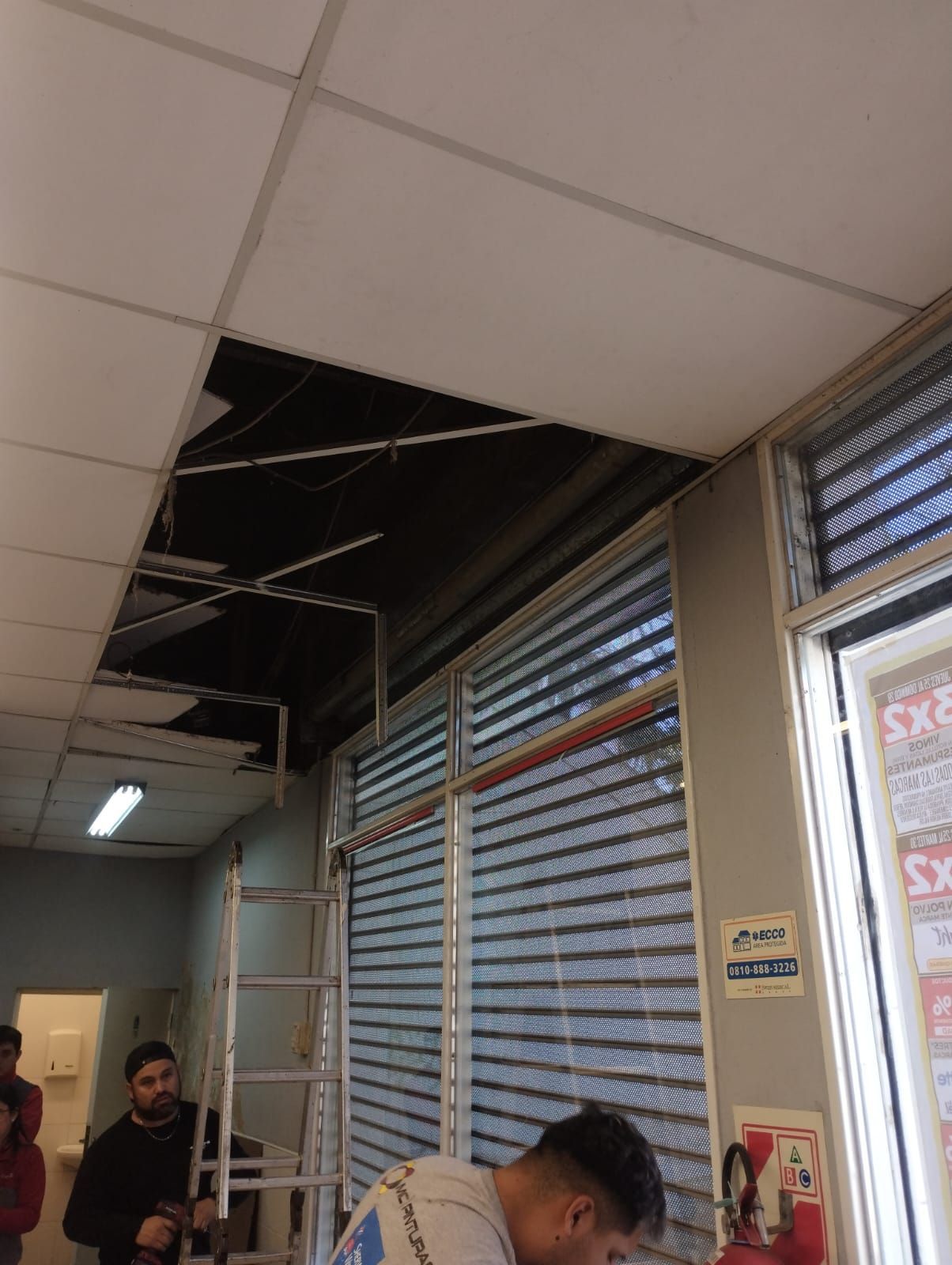 Un hombre está trabajando en el techo de una habitación con una escalera.